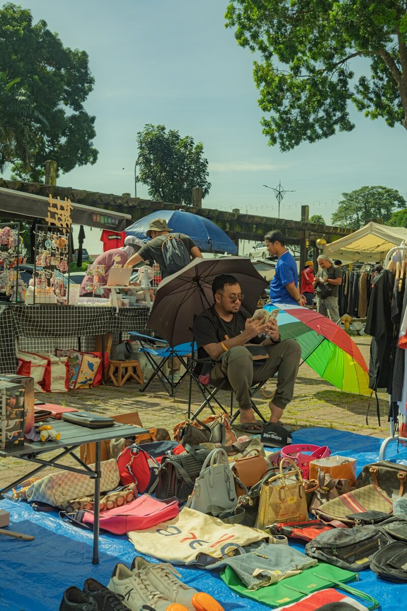 People browsing goods at an outdoor market under umbrellas